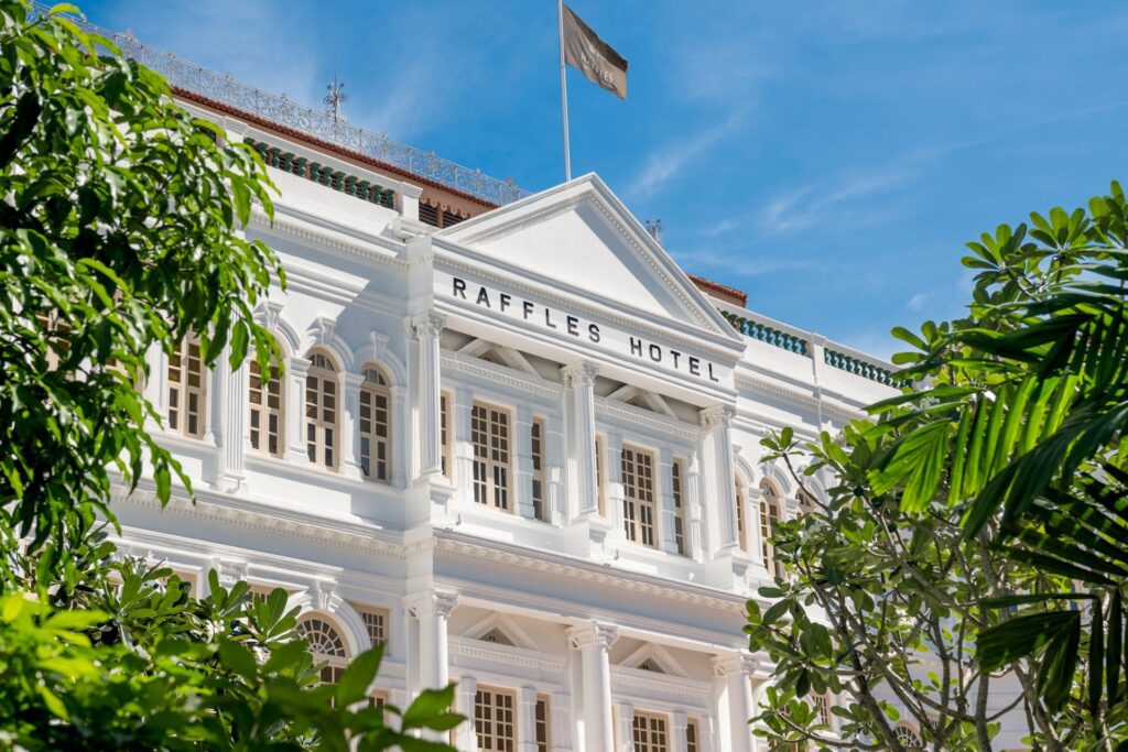 Colonial style Raffles hotel facade framed by palms, Raffles brand imagery for Raffles Residences The Palm